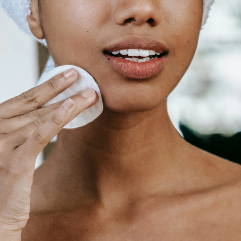 Imagem de uma modelo de cor negra limpando a pele com algodão ilustrando o texto A pele humana: estrutura, funções, tipos e características