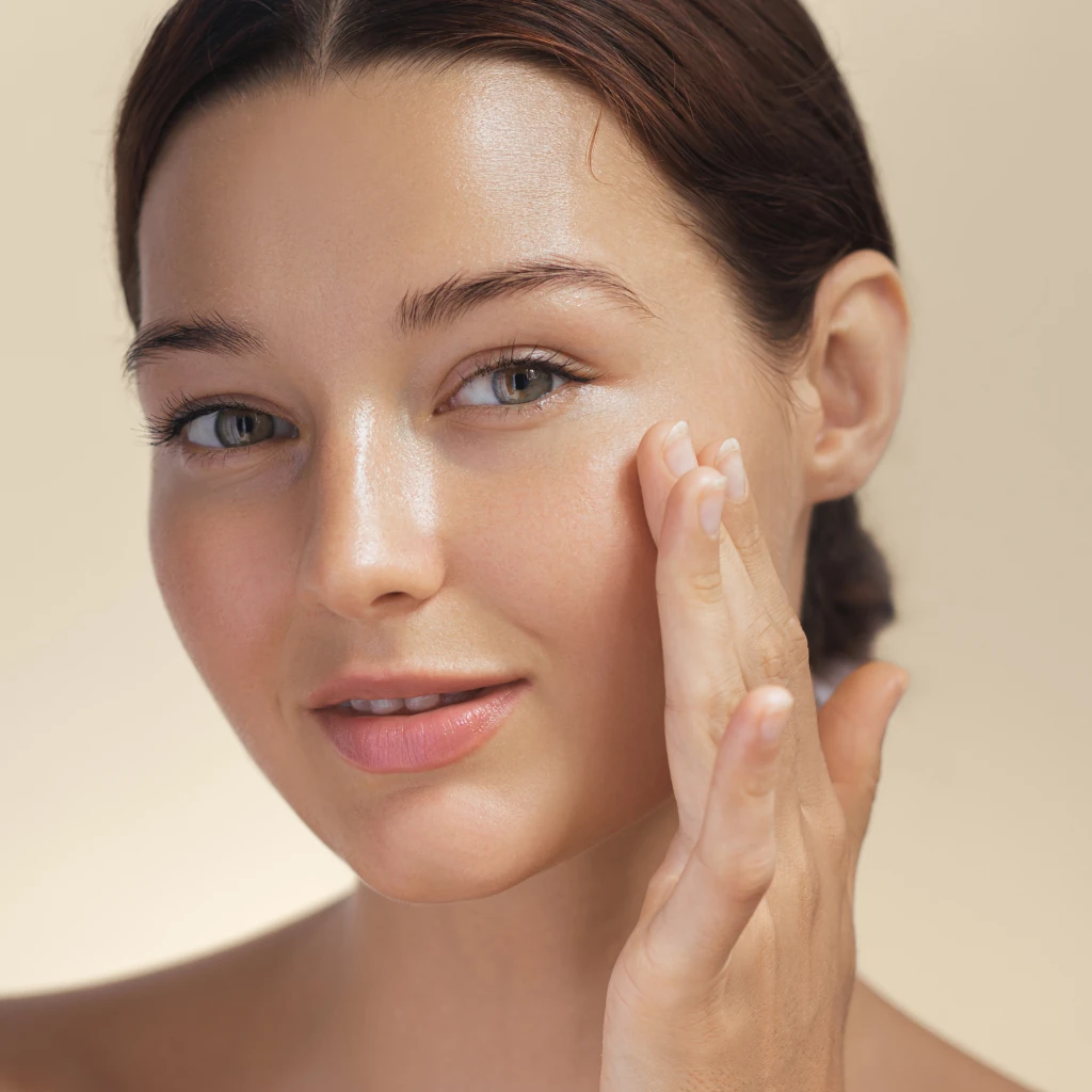 Close em um rosto feminino com uma mão sobre a pele ilustrando o texto Guia completo sobre pele oleosa: causas, tratamentos e as melhores dicas de cuidados