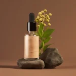 Imagem de um frasco de cosmético sobre uma pedra e à frente de uma planta com flores amarela ilustrando o texto Como funciona a cosmética natural: benefícios, práticas e impactos positivos
